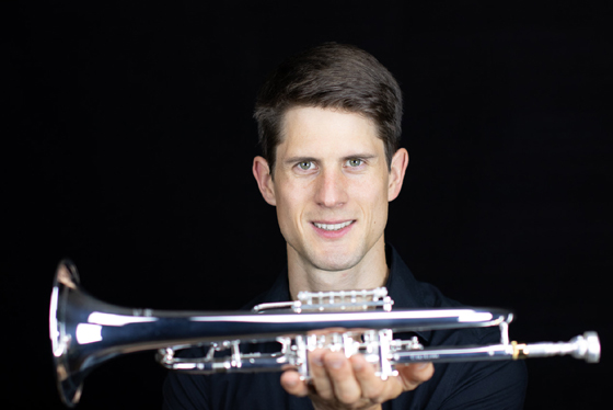 Das Bild zeigt Stefan Leitner mit einer Trompete in der Hand. Er unterrichtet als Musiklehrer das Fach Trompete an der Musikschule Mittelsachsen.
